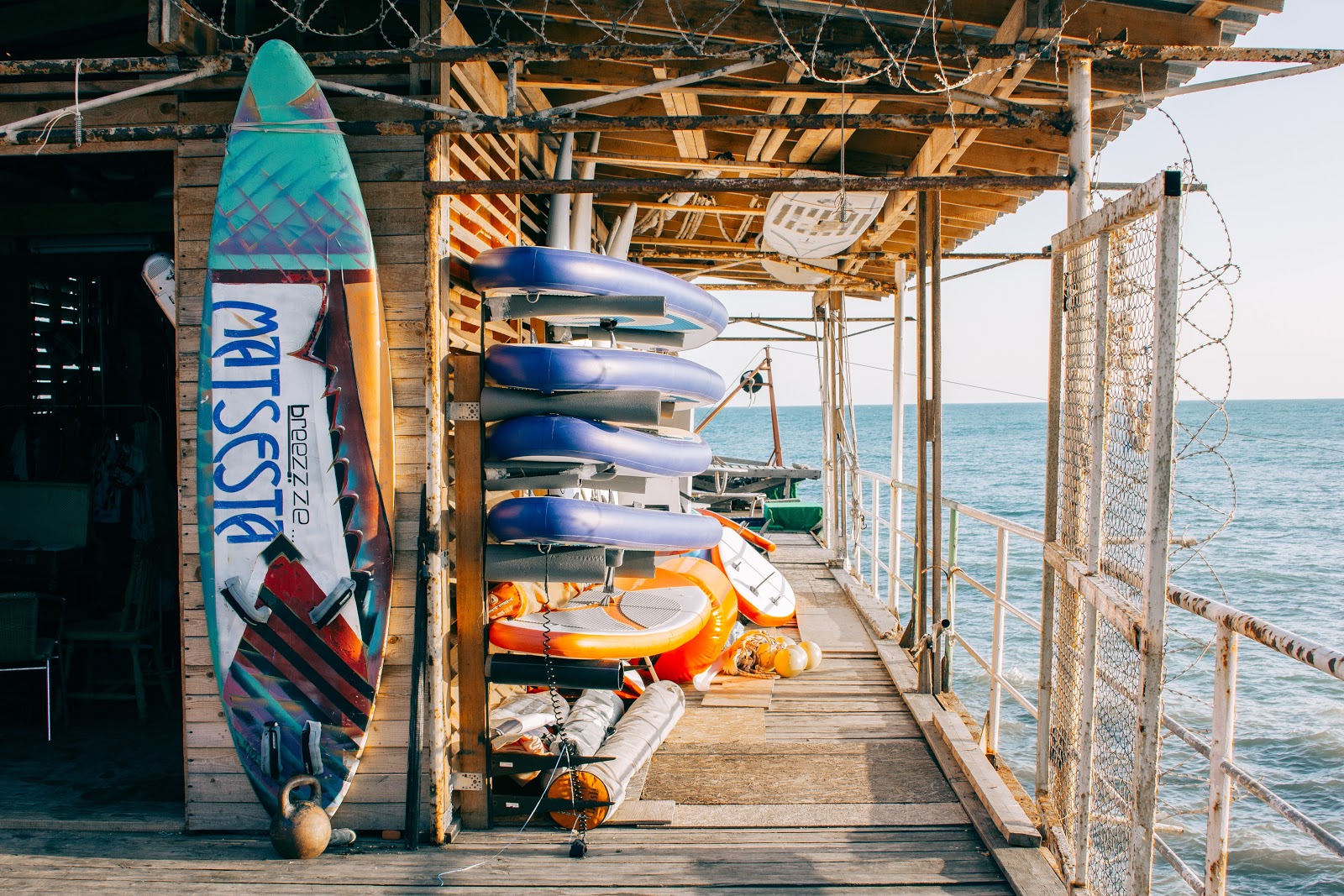 Surfboard and kayaks along the pier overlooking the ocean