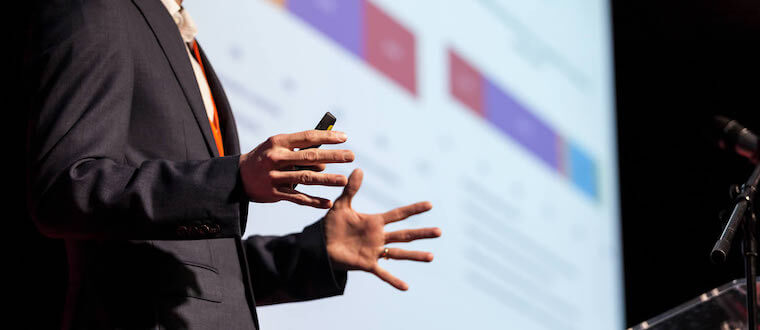 a man standing on a podium with his hands out while presenting