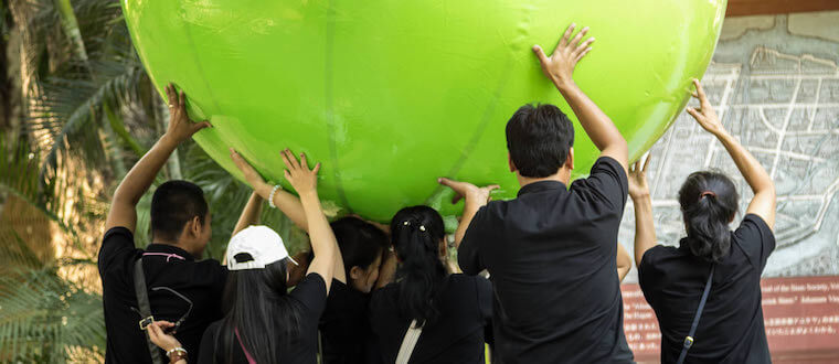 a group of people working together to hold up a large inflatable ball