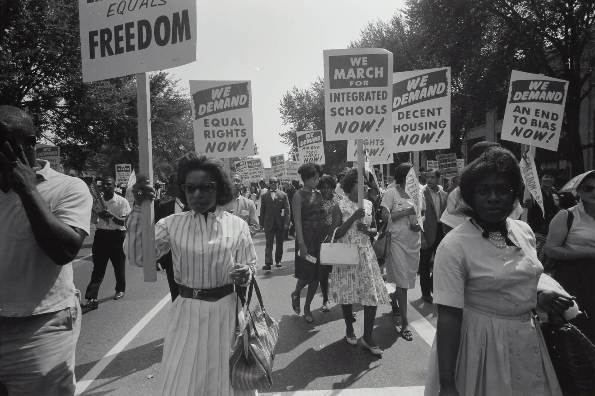 Black and white image of people marching for equal rights holding placards and signs