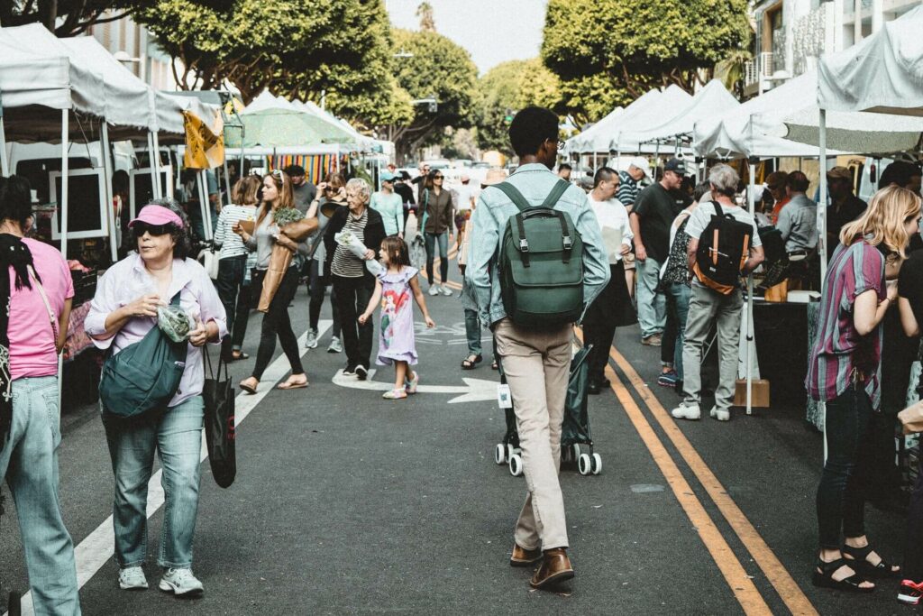 People walking around an open air market with tents